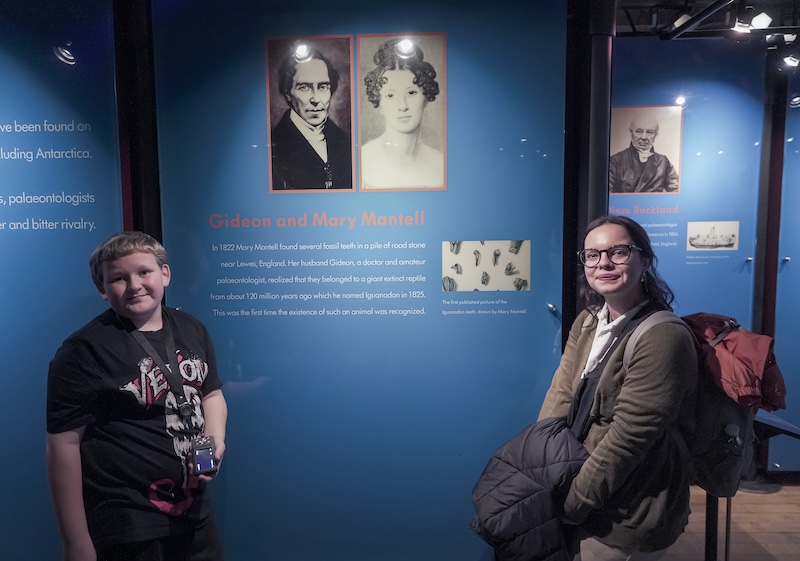 Yaz and Arthur in front of museum panels showing into about Gideon and Mary Mantell